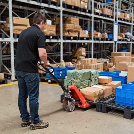 Warehouse worker dragging hand pallet truck or manual forklift with the shipment pallet unloading into a truck. Distribution, Logistics Import Export operation, Trading, Shipment, Delivery concept